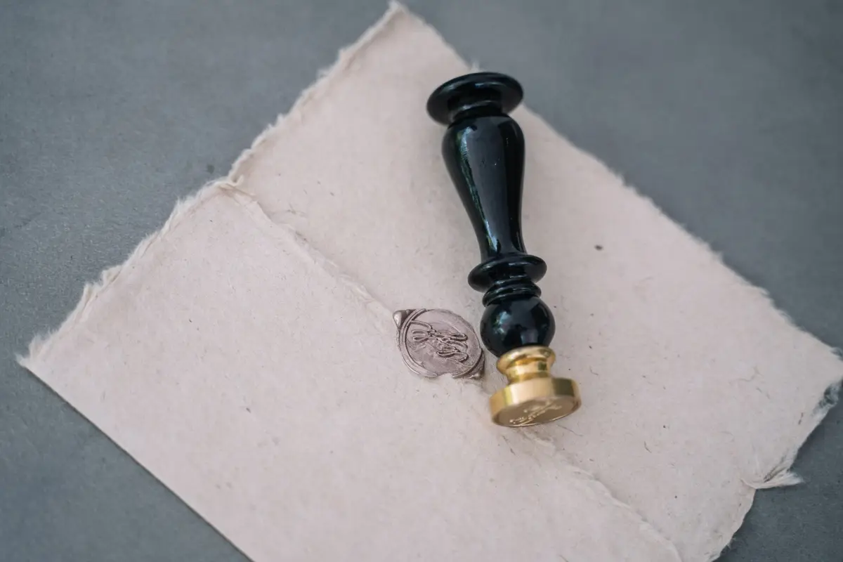A wax seal stamp pressed onto a handmade paper envelope