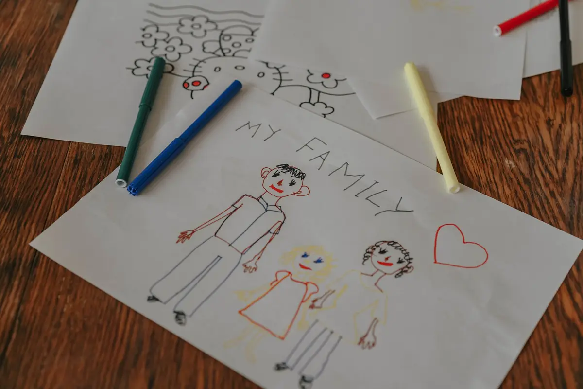 A child's crayon drawing of their family on a wooden floor