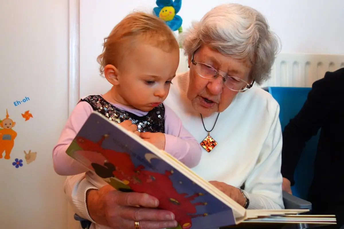 A grandmother reading a picture book to a toddler on her lap