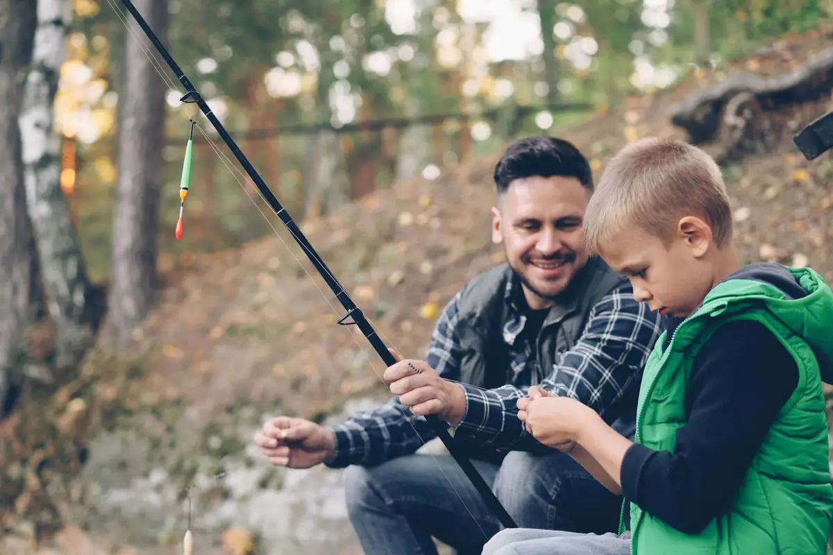 A father and his young son fishing together by a lake