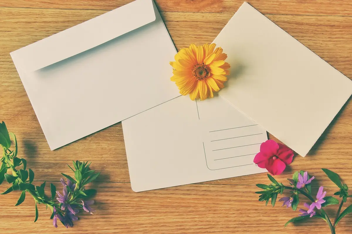 Blank cards and envelopes with fresh flowers on a wooden table
