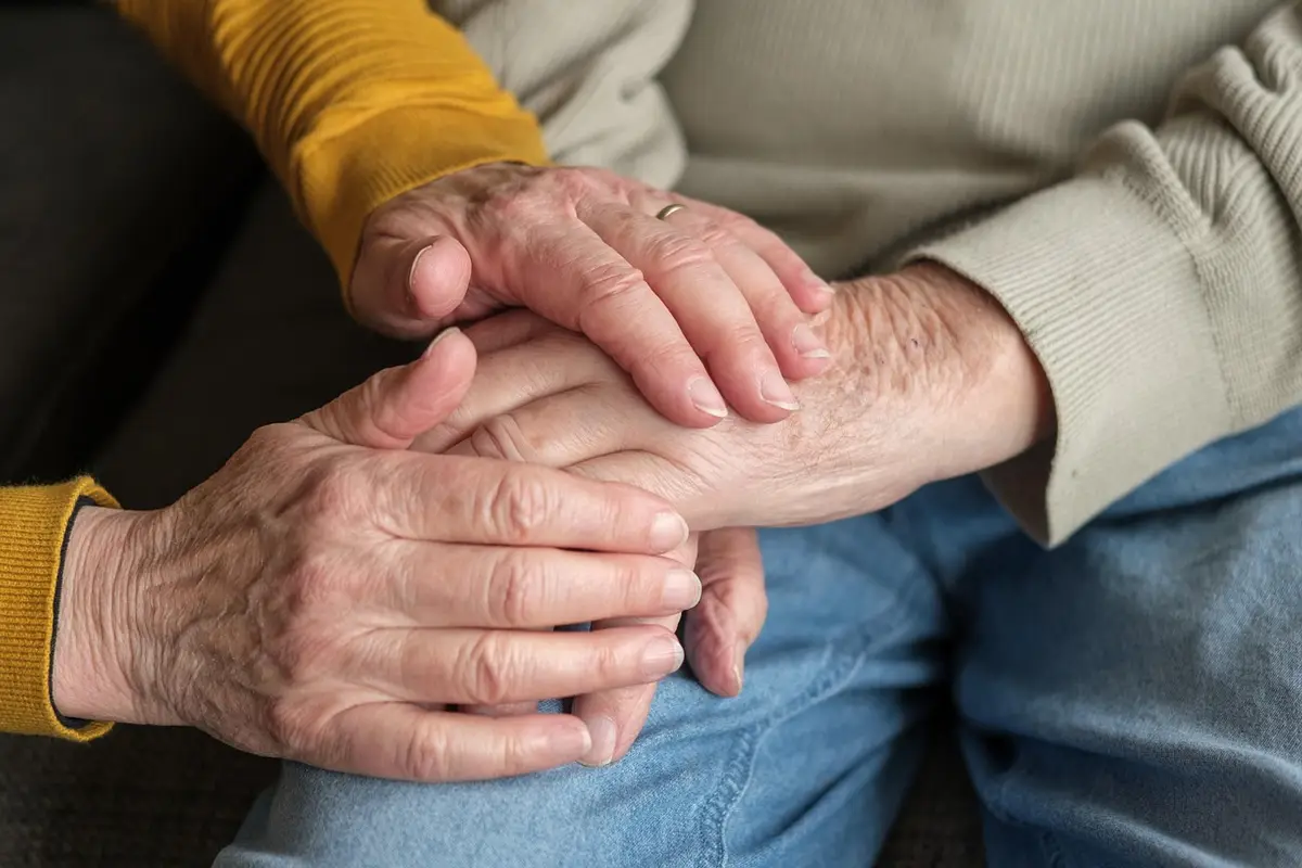 An older couple's hands, one resting gently on the other