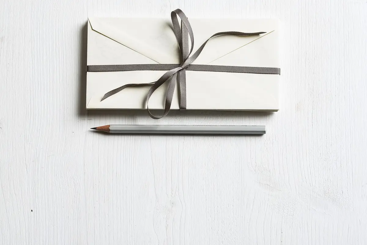 A bundle of letters tied with a ribbon beside a pencil