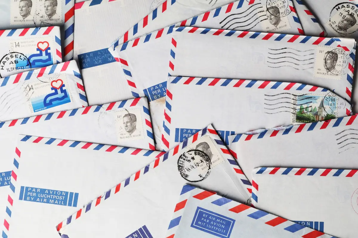 A pile of airmail envelopes with red and blue borders and stamps