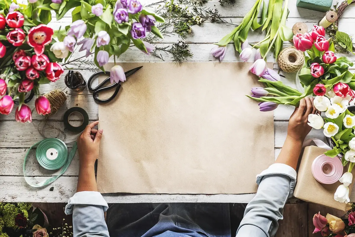 Brown craft paper on a table surrounded by flowers, twine and scissors