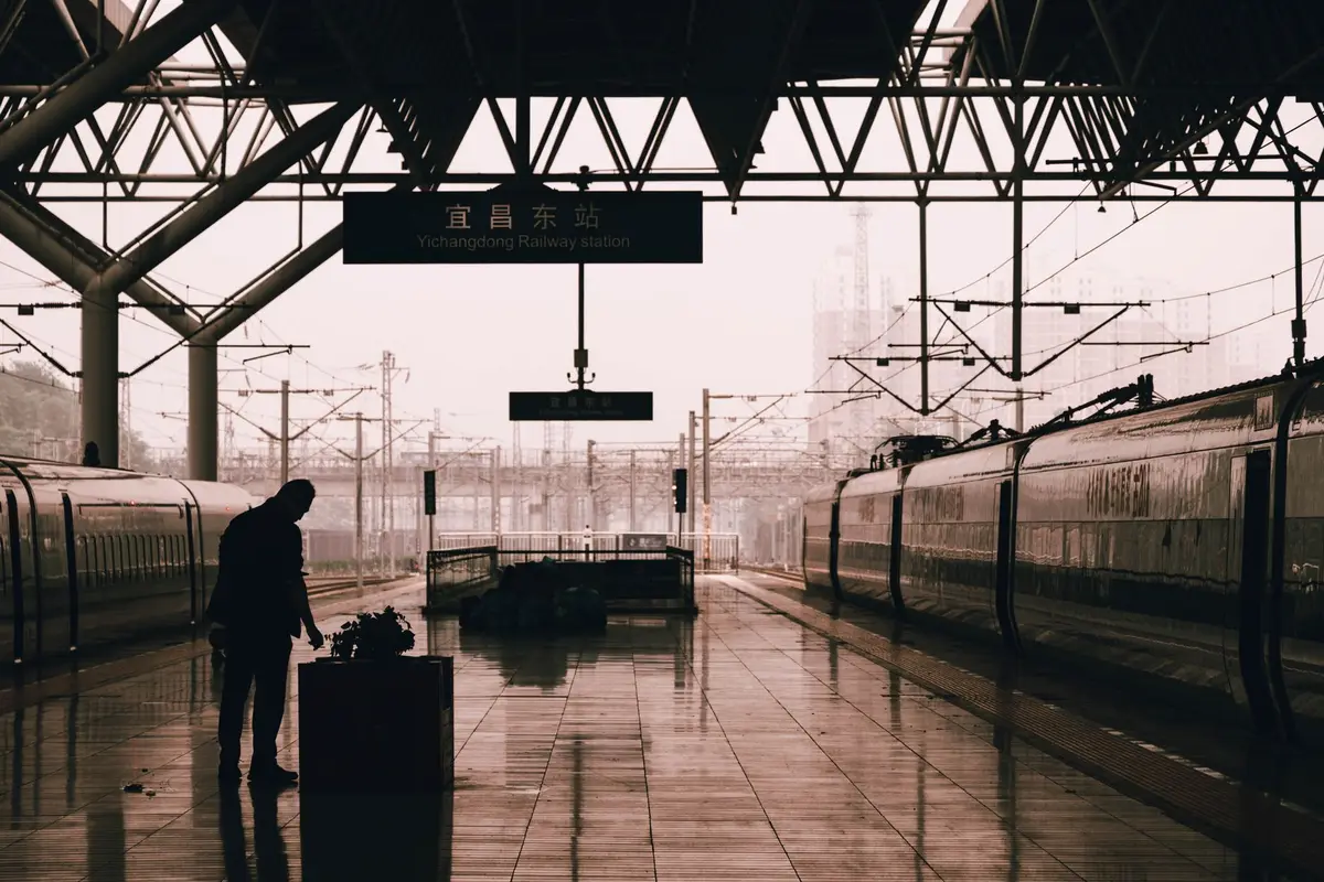A traveler with a suitcase on an empty train platform at dawn