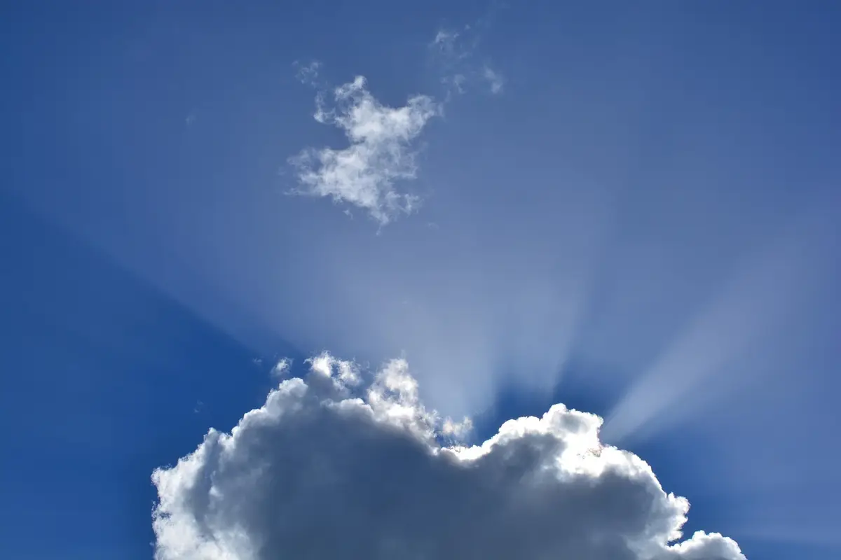 Sunlight breaking through a white cloud in a blue sky