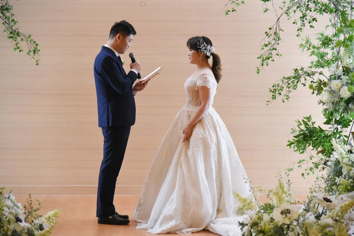 A bride and groom reading their vows to each other at an outdoor wedding